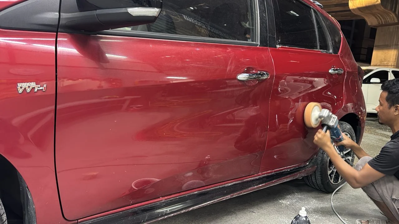A Speedy Spray technician polishing the side of a red MPV