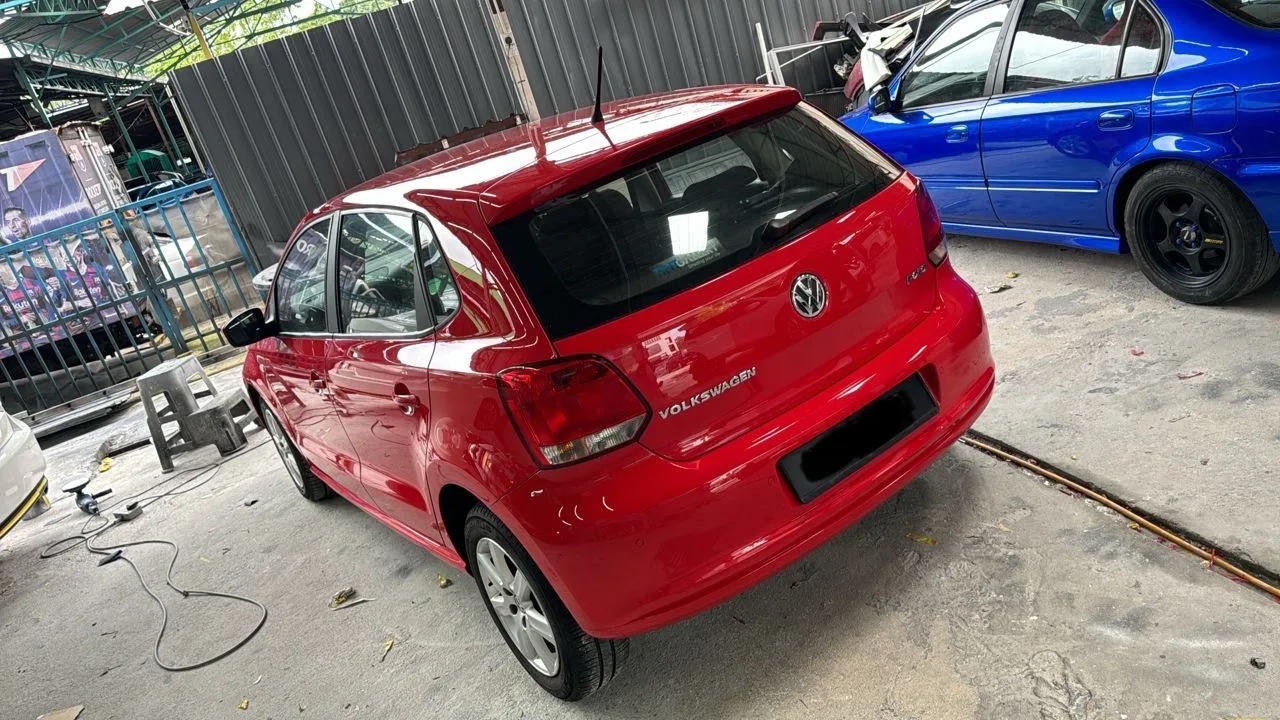 Rear and side view of a red Volkswagen hatchback after refinishing at Speedy Spray